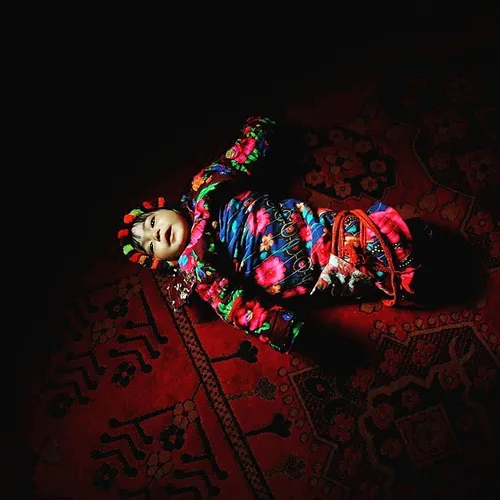 Afghan baby, Lalah, lies on the floor inside a tent at a 