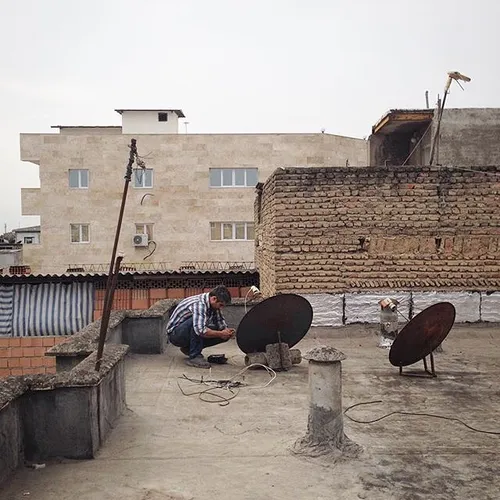 A man installing a satellite dish at a rooftop. Sari, Maz