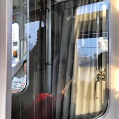 Commuters are reflected on door's window of a train in a 