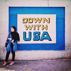 A young #Iranian woman stands in front of an anti U.S. Sl