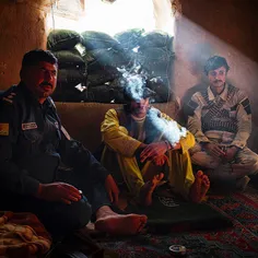 Afghan national police, in and out of uniform, sit and sm