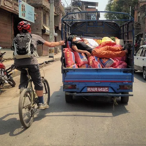 A foreigner riding his bicycle takes a help from a loaded