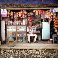 A Nepalese man reads newspaper while he waits for custome