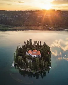 ‏دریاچه‌ای آرام با جزیره‌ای کوچک در پارک ملی کرکا (Krka) 