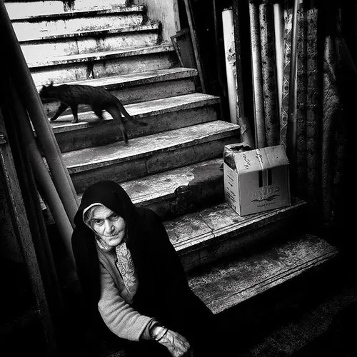 An old woman resting on some stairs in the bazaar of Rash