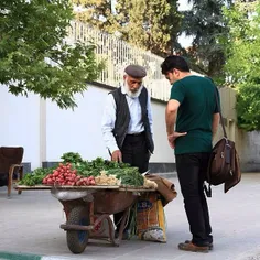 A vendor sells fresh vegetables by the side of a street. 