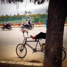 A rickshaw puller takes nap on the road side of Kathmandu