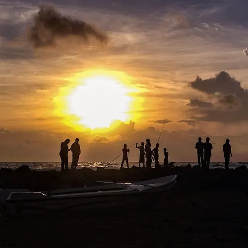 The sun sets behind people fishing on a jetty in Mount La