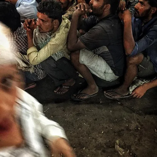 Indian men wait for food donated by muslims during the ho