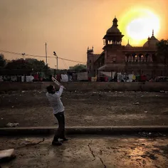 An Indian boy plays gully cricket in front of Jama Masjid