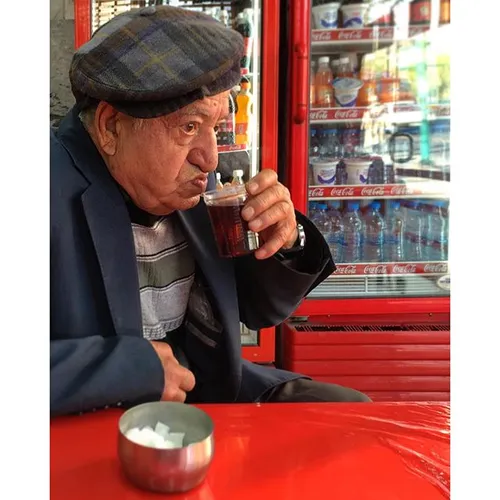 An elderly gentleman is having tea in a humble teahouse. 