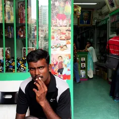 A migrant worker waits outside a photo lab in Little Indi