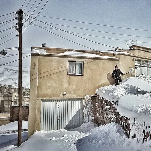 A man shoveling snow off the front entrance of his house.