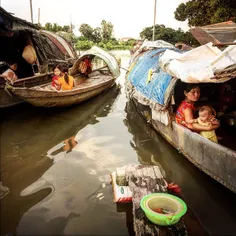 A woman take care of her son on their makeshift houseboat