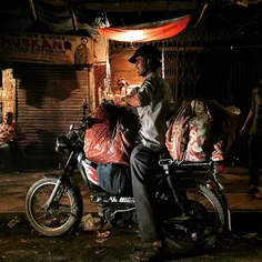 An Indian vendor carries goods on his moped as he sells t