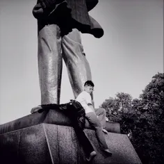 Boys try to reach up the statue of Lenin as a game on sun