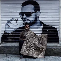 A vendor selling carpets takes a rest in front of a close