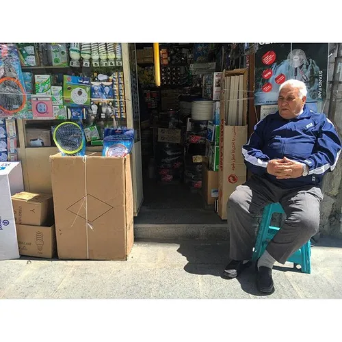 A gentleman is sitting outside his shop in Naserkhosro, d