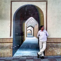 A man leans against a wall on which a mural's been applie