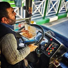 A BRT driver has lunch as he drives through Valiasr St. I