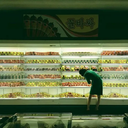 A woman reorganizes the canned food aisle at a Pyongyang 