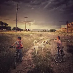Boys riding their bikes on an open field at Qal’e Village