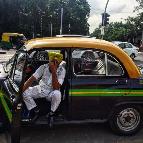 An Indian Sikh taxi driver sits tiredly in his classical 
