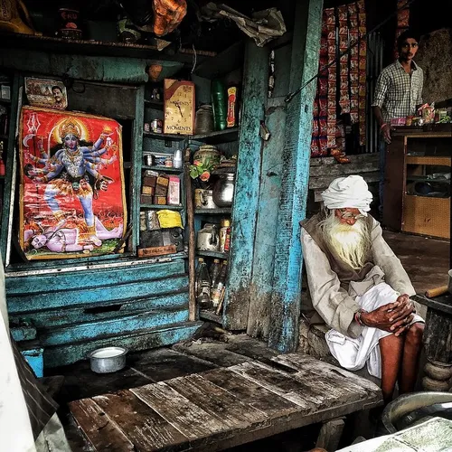 An Indian elderly person sits at his roadside makeshift t