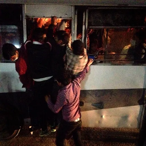 Nepalese people hang on a completely crowded bus to reach