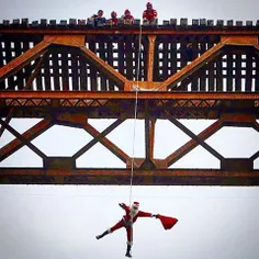 A man dressed as Santa Claus descends from a bridge to de