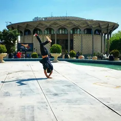A boy performs acrobatics in front of City Theater of Teh