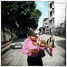 A badger Roma violinist with his daughter playing violin 