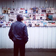 A man looking at daily local newspapers hanged up on the 