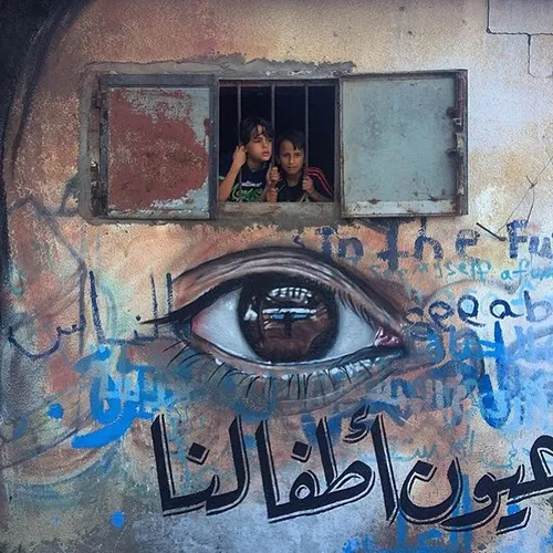 Two Palestinian children look out of a window on a wall p