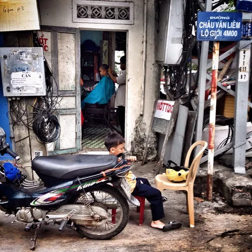 A boy sits nearby the street as he waits for his turn to 
