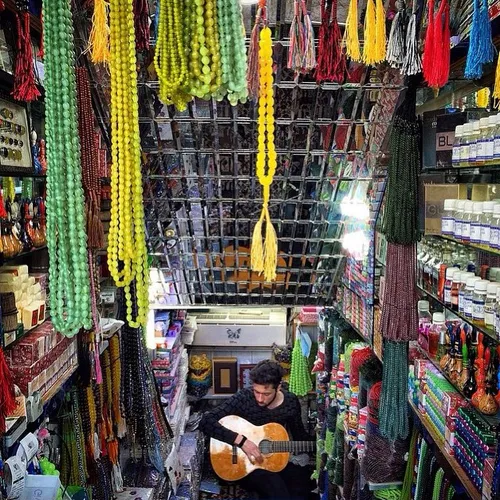 A man playing the guitar at his souvenir gift shop. Mashh