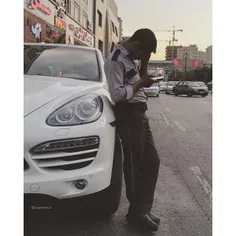 A parking attendant is leaning against a luxury car. | 14