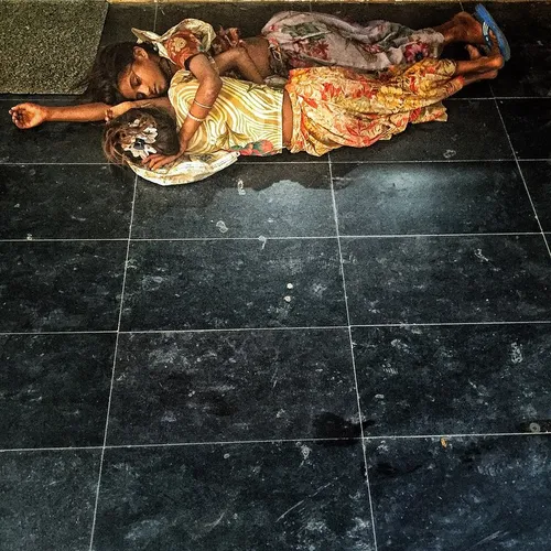 Two young Indian girls sleep on the pavement near the air