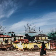 A woman walks by a painted wall. #Sary, #Mazandaran, #Ira