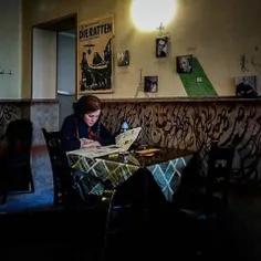 A young woman reads a newspaper in a cafe downtown. #Iran