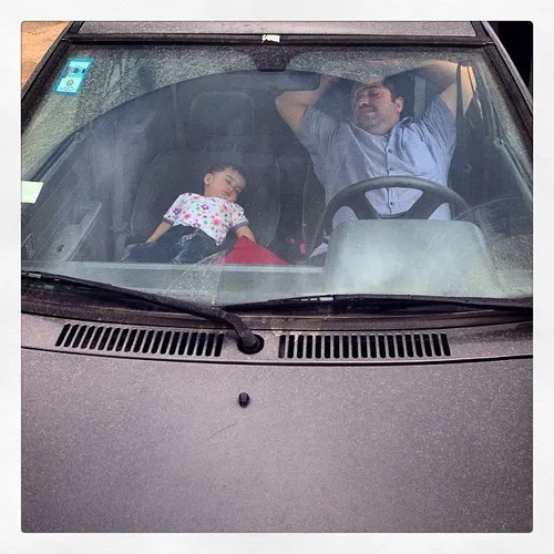 Father and son take a nap in their car. Tehran, Iran. Pho