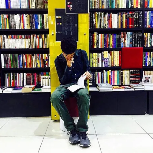 A man reads a book in a book store. Tehran, Iran. Photo b