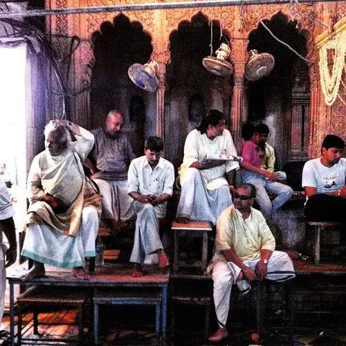 Indian men sit under the fans at a courtyard outside a te