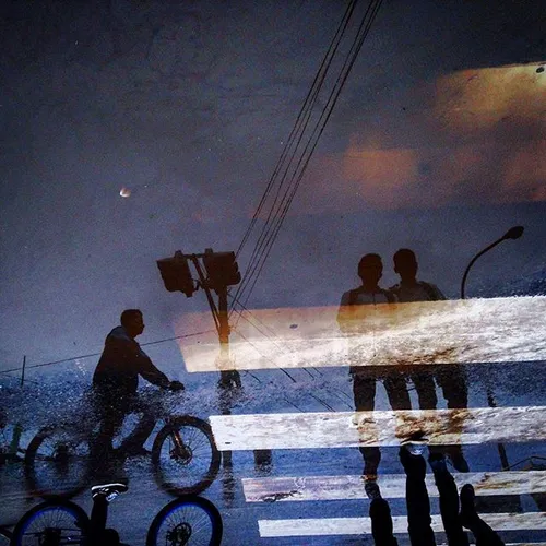 Reflection of pedestrians are seen on the road after rain