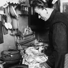 زنی در حال روشن کردن اجاق خوراک پزی خود با اسکناس در سال 