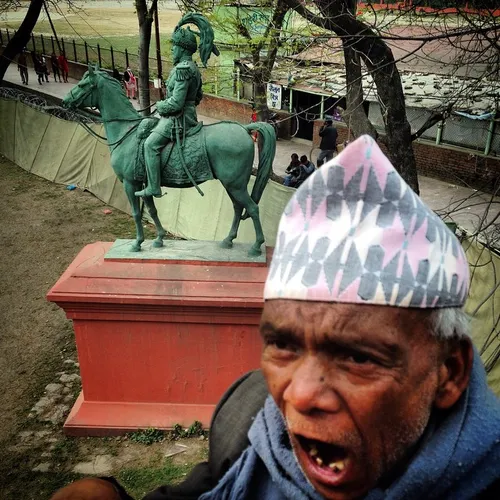 A Nepalese elderly man yawns near the statue of Rana Prim