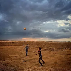 Young Syrian boys kick a football at an informal refugee 
