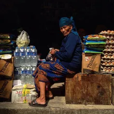 An elderly Gurung community woman reacts as she shops at 