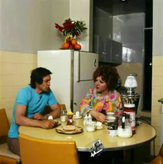 رضا بیک ایمانوردی هنرمند محبوب سینما و همسرش در کنار میز 
