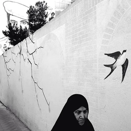 A woman in chador walks on a sidewalk. The portrait of an